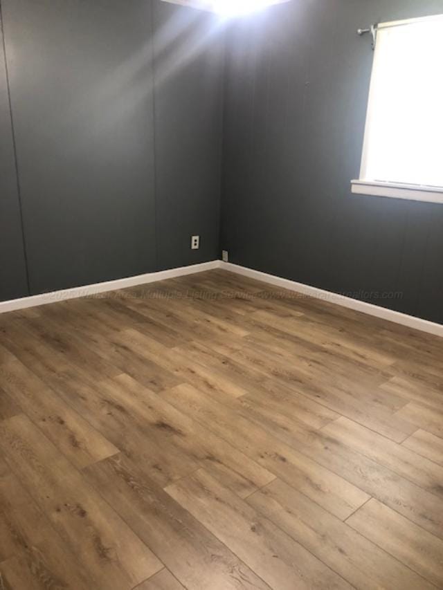 unfurnished room featuring wood-type flooring and baseboards