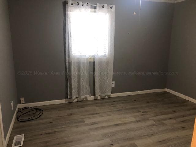 empty room with visible vents, wood finished floors, and baseboards