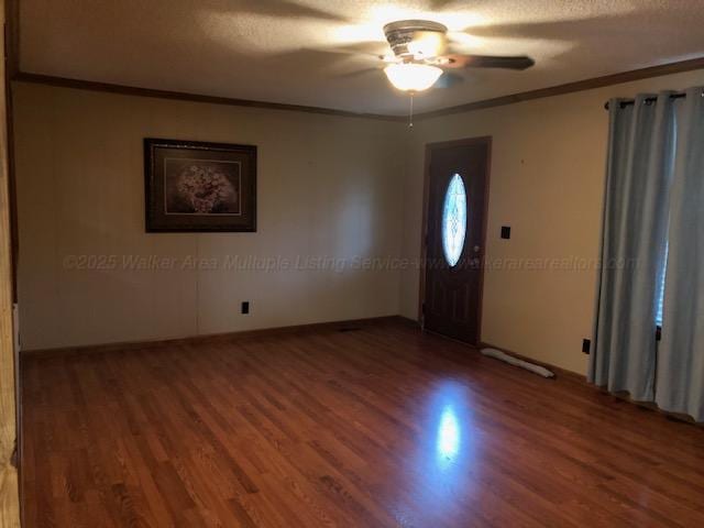 foyer entrance featuring crown molding, baseboards, wood finished floors, and a ceiling fan