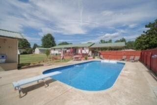 view of swimming pool with a patio area, a diving board, a fenced in pool, and fence