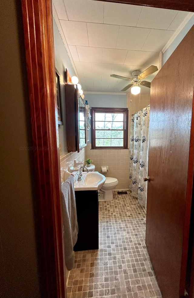 full bathroom featuring a shower with shower curtain, toilet, vanity, a ceiling fan, and tile walls