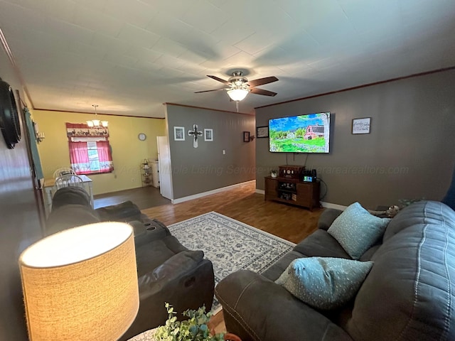 living room with ceiling fan with notable chandelier, wood finished floors, baseboards, and ornamental molding