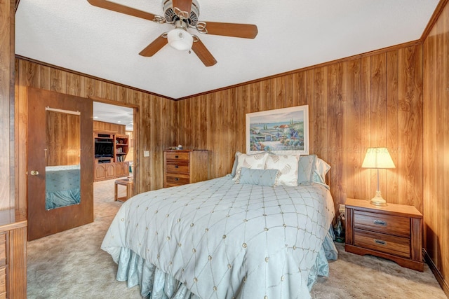 bedroom with a ceiling fan, crown molding, wooden walls, and light colored carpet