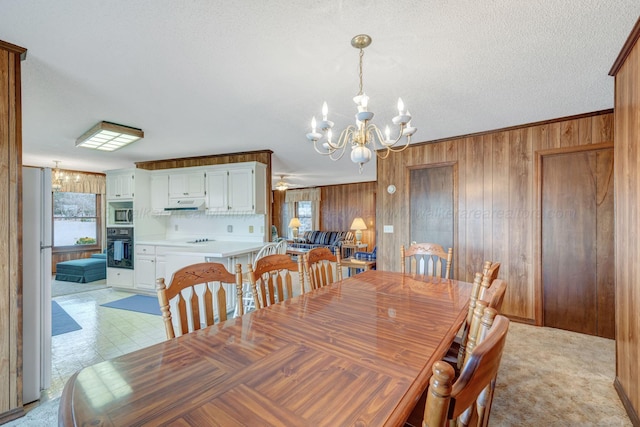 dining area featuring a textured ceiling, wood walls, a healthy amount of sunlight, and a notable chandelier