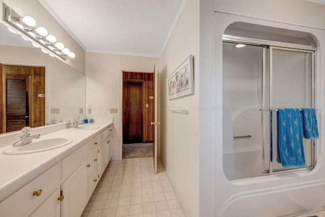 full bathroom with a shower with door, a textured ceiling, a sink, and crown molding