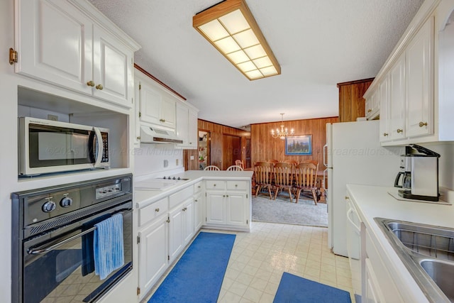 kitchen featuring white cabinets, a peninsula, under cabinet range hood, and white appliances