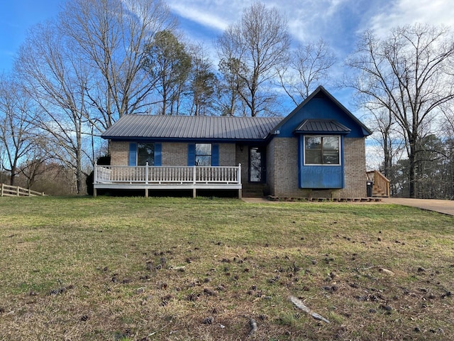 view of front of property with fence, a wooden deck, metal roof, a front yard, and brick siding
