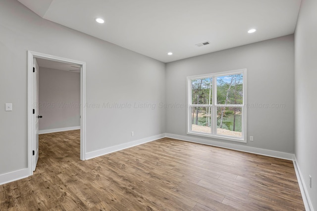 spare room with baseboards, visible vents, recessed lighting, and wood finished floors