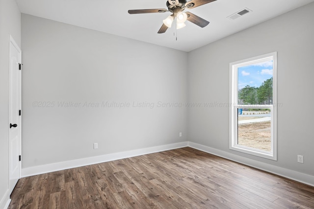 spare room featuring baseboards, visible vents, wood finished floors, and a ceiling fan