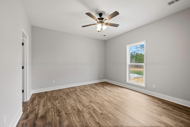 spare room featuring baseboards, visible vents, wood finished floors, and ceiling fan
