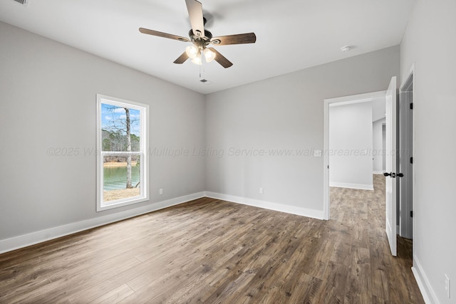 empty room with a ceiling fan, visible vents, baseboards, and wood finished floors