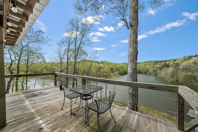 wooden terrace featuring a wooded view and a water view