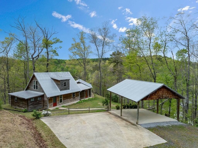 view of front of house featuring a porch, driveway, and a view of trees