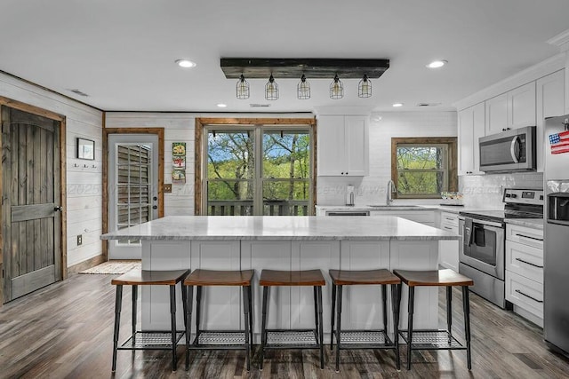 kitchen with stainless steel appliances, a sink, a breakfast bar area, and a healthy amount of sunlight