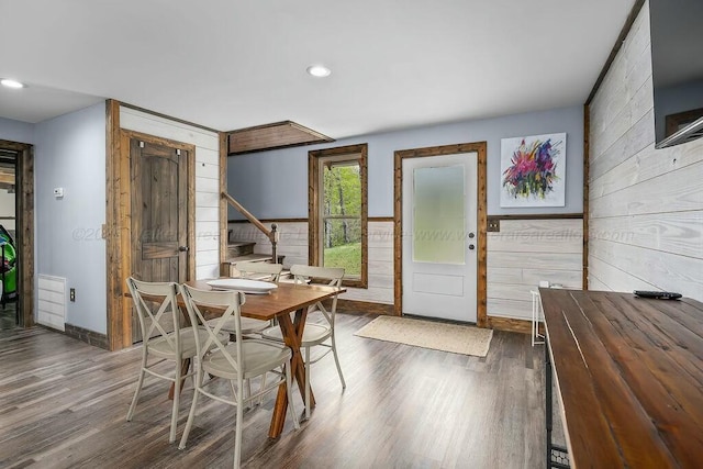 dining room featuring recessed lighting, wooden walls, wood finished floors, and baseboards