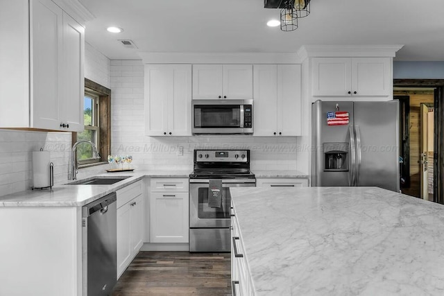 kitchen with white cabinets, light stone countertops, a sink, and appliances with stainless steel finishes