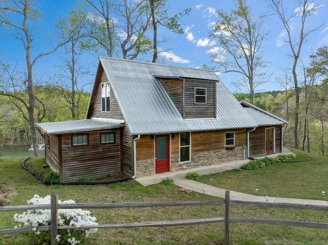 rustic home featuring fence private yard, stone siding, a front yard, and metal roof