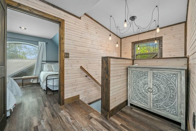 stairway featuring wood finished floors, wood walls, and a notable chandelier