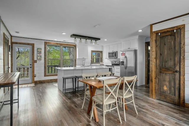 dining room with wood walls, dark wood-type flooring, visible vents, and recessed lighting