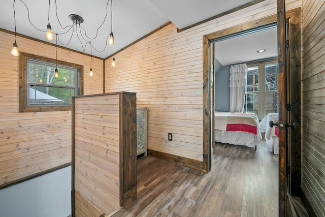 corridor featuring vaulted ceiling, a healthy amount of sunlight, and wooden walls