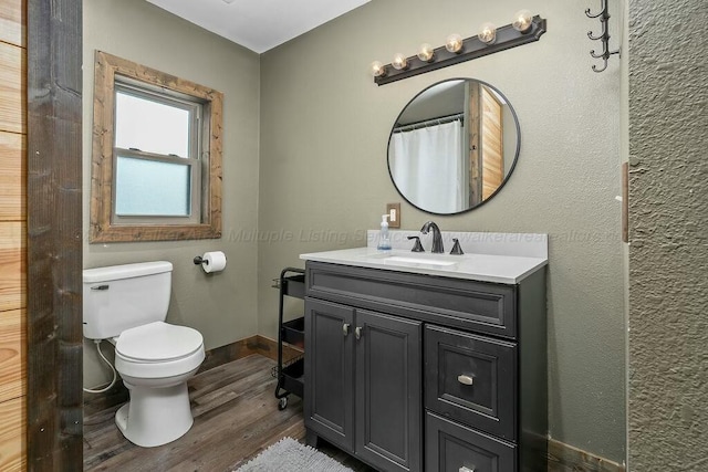 bathroom featuring toilet, vanity, and wood finished floors