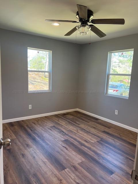 spare room with baseboards, dark wood-style floors, a wealth of natural light, and a ceiling fan