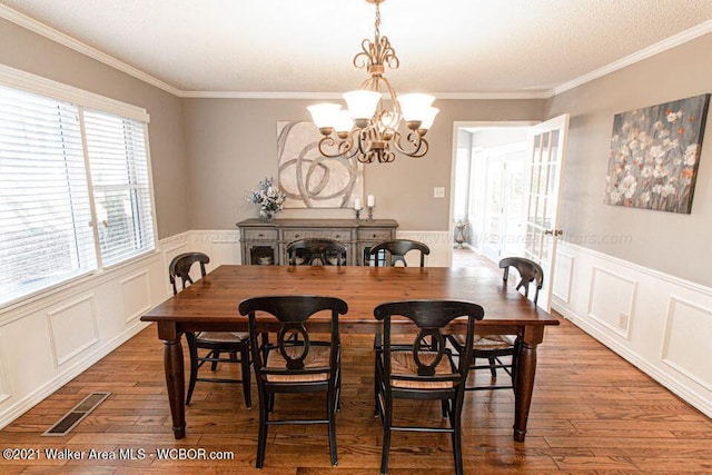 dining area with dark hardwood / wood-style floors, crown molding, and a notable chandelier