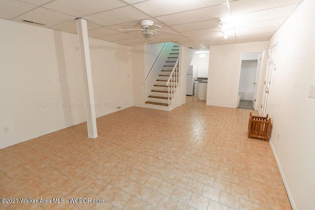 basement featuring white refrigerator and a paneled ceiling