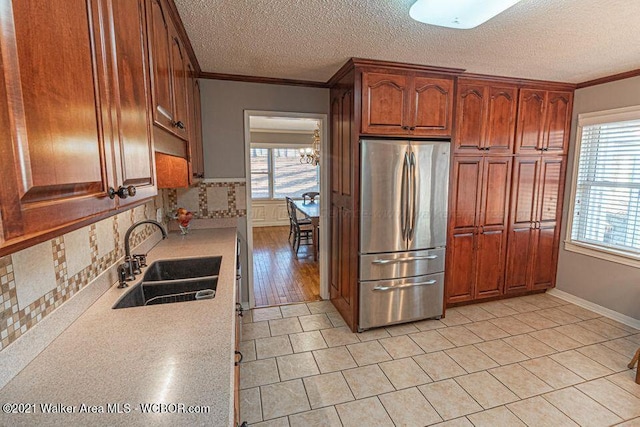 kitchen with plenty of natural light, stainless steel fridge, crown molding, and sink