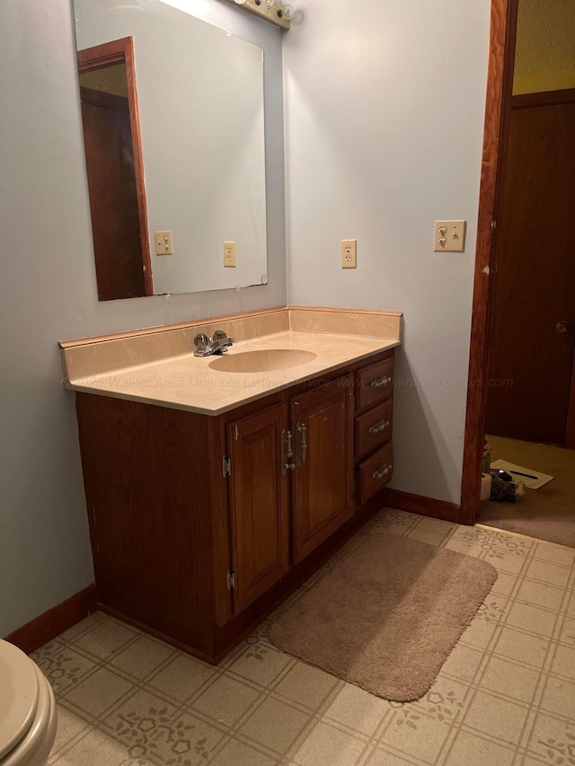 bathroom featuring baseboards, toilet, vanity, and tile patterned floors