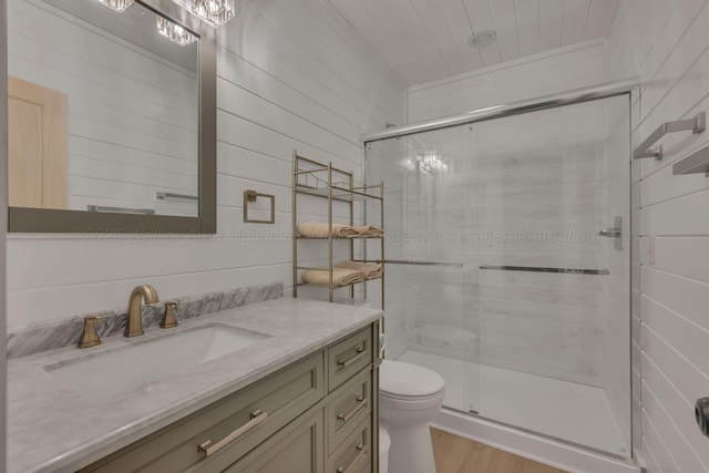 bathroom with toilet, a stall shower, wood finished floors, and vanity