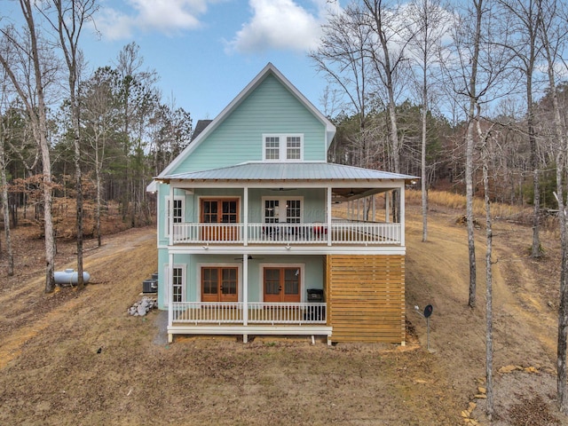 back of property with metal roof, a porch, a balcony, and a ceiling fan