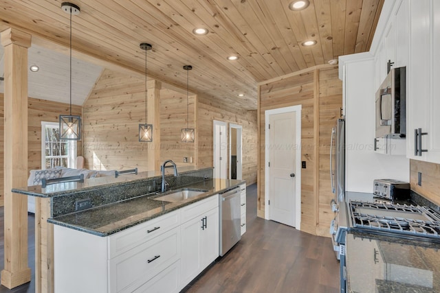 kitchen featuring wood ceiling, wooden walls, appliances with stainless steel finishes, and a sink