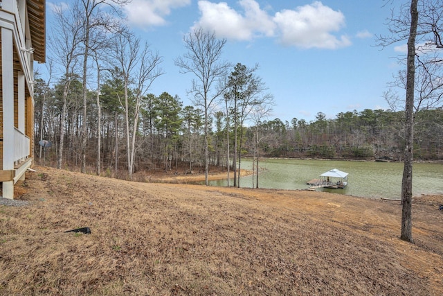 view of yard with a water view, a forest view, and a boat dock