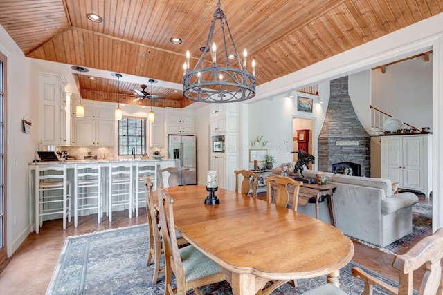 dining space featuring wood ceiling, a stone fireplace, lofted ceiling, baseboards, and recessed lighting