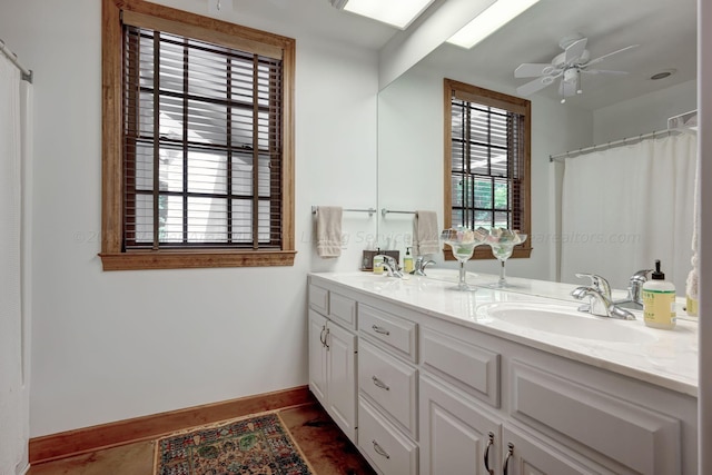 full bath with a sink, a ceiling fan, tile patterned flooring, baseboards, and double vanity
