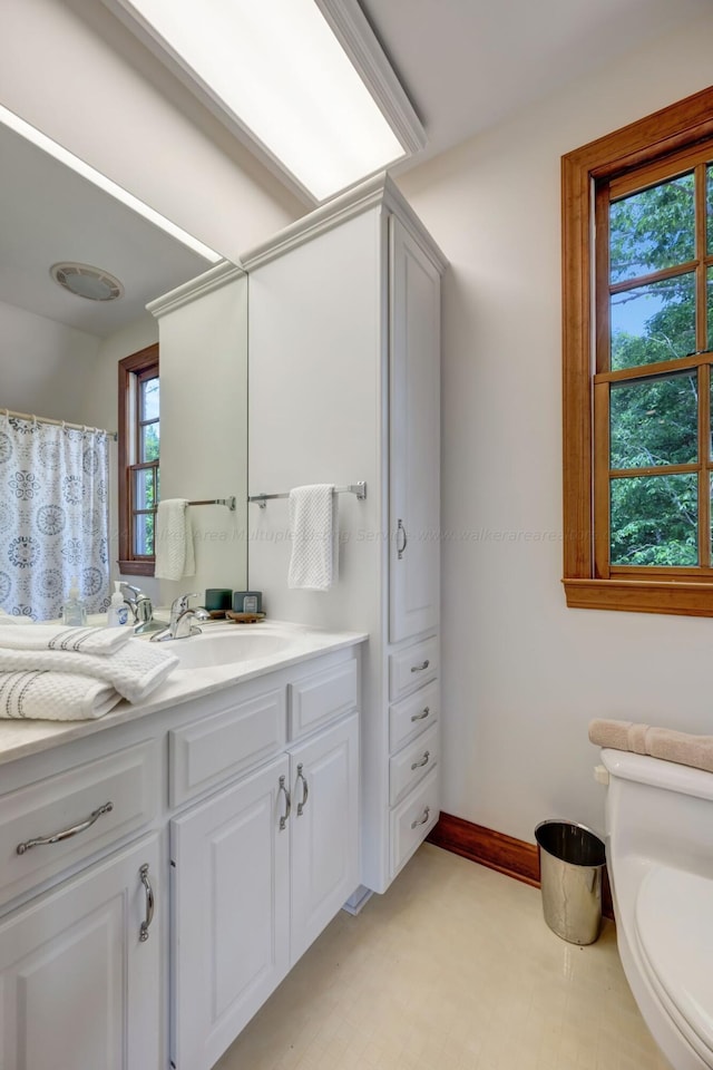 full bath featuring vanity, toilet, a shower with shower curtain, baseboards, and tile patterned floors