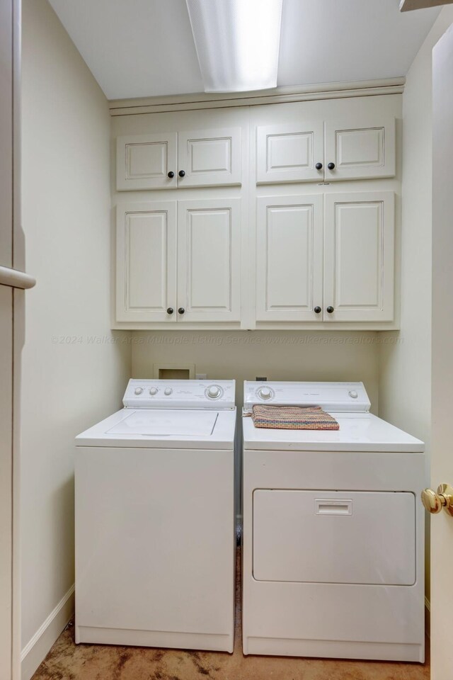washroom with baseboards, washer and dryer, and cabinet space