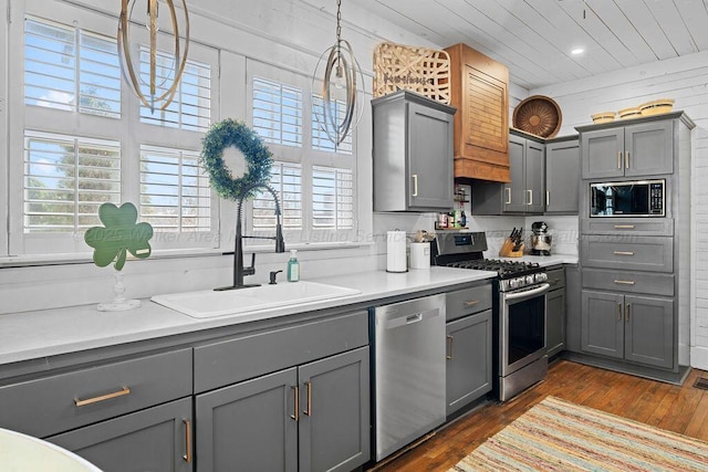 kitchen with light countertops, stainless steel appliances, dark wood-type flooring, a sink, and gray cabinetry