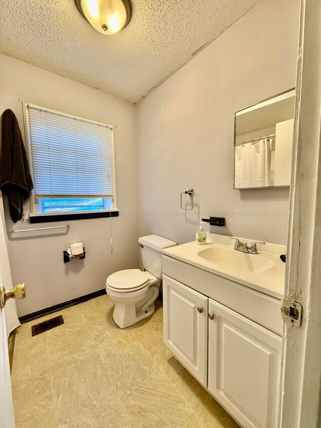 full bath with visible vents, toilet, vanity, and a textured ceiling