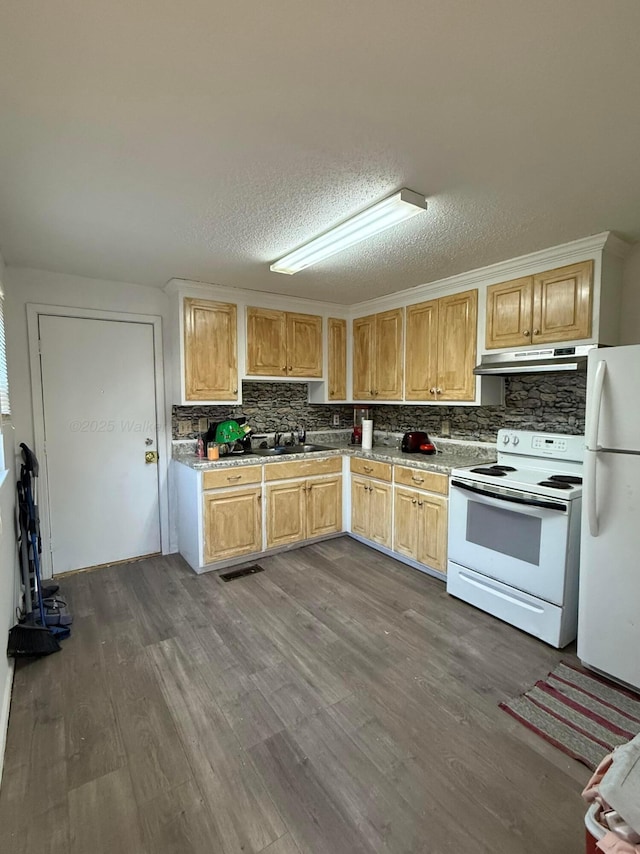 kitchen with dark wood-type flooring, under cabinet range hood, tasteful backsplash, and white appliances