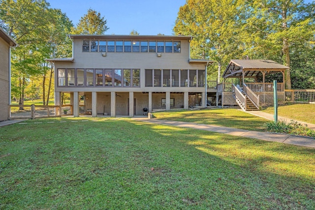 back of house featuring a gazebo, a sunroom, a deck, and a lawn