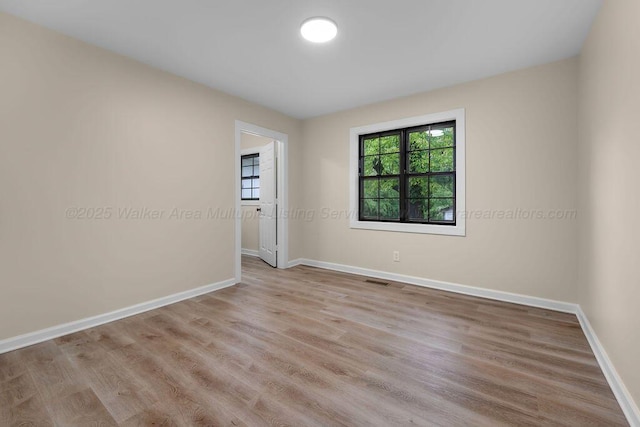 unfurnished room with visible vents, wood finished floors, and baseboards