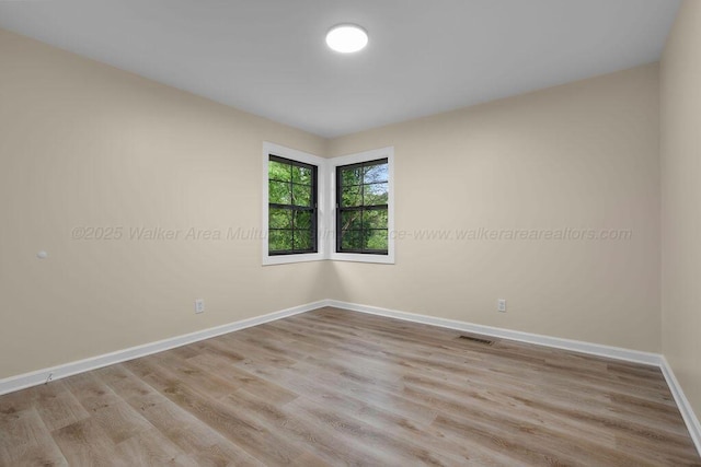 spare room with baseboards, wood finished floors, and visible vents