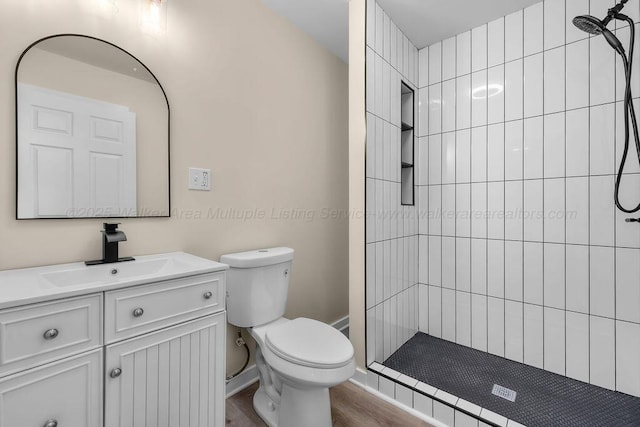 bathroom with wood finished floors, vanity, a shower stall, and toilet