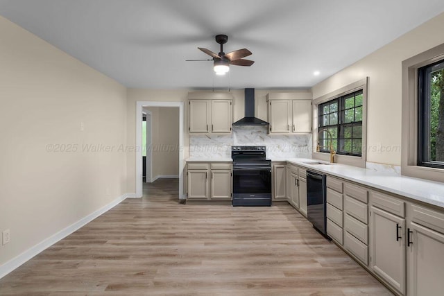 kitchen with a ceiling fan, a sink, plenty of natural light, black appliances, and wall chimney exhaust hood