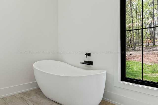 full bathroom with baseboards and a freestanding tub