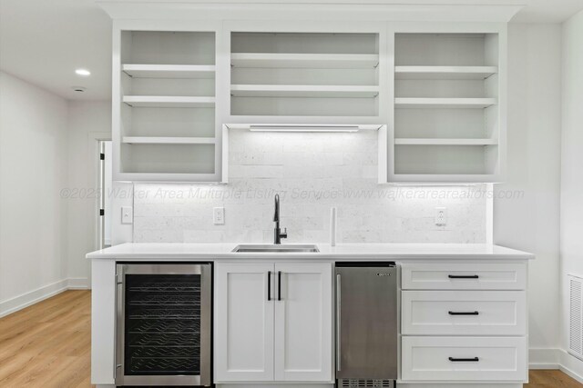 bar with backsplash, baseboards, a sink, and wine cooler