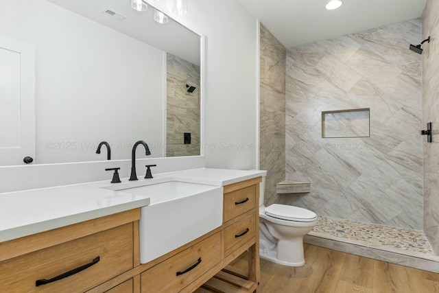 bathroom featuring toilet, wood finished floors, visible vents, a shower stall, and vanity