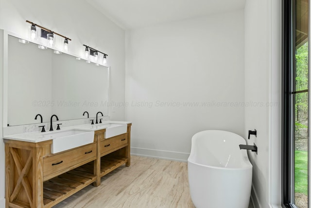 bathroom featuring baseboards, a soaking tub, double vanity, and a sink